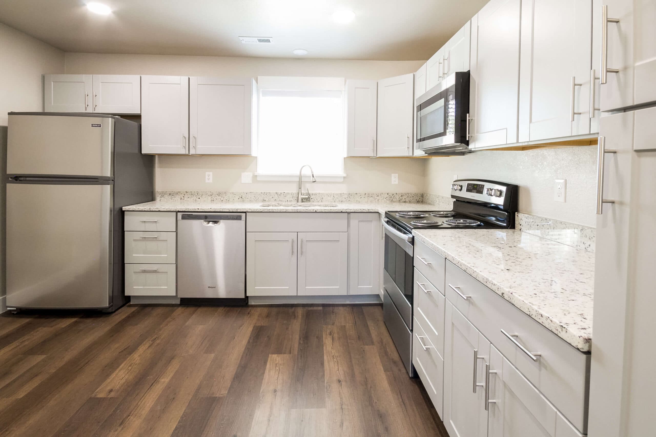 Full kitchen with white cabinets and stainless appliances in a furnished Twin Cedar crew unit in Vernal, Utah