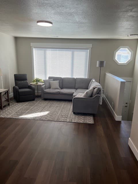 Furnished living room with a sofa, recliner, and hardwood floors in a Twin Cedar apartment