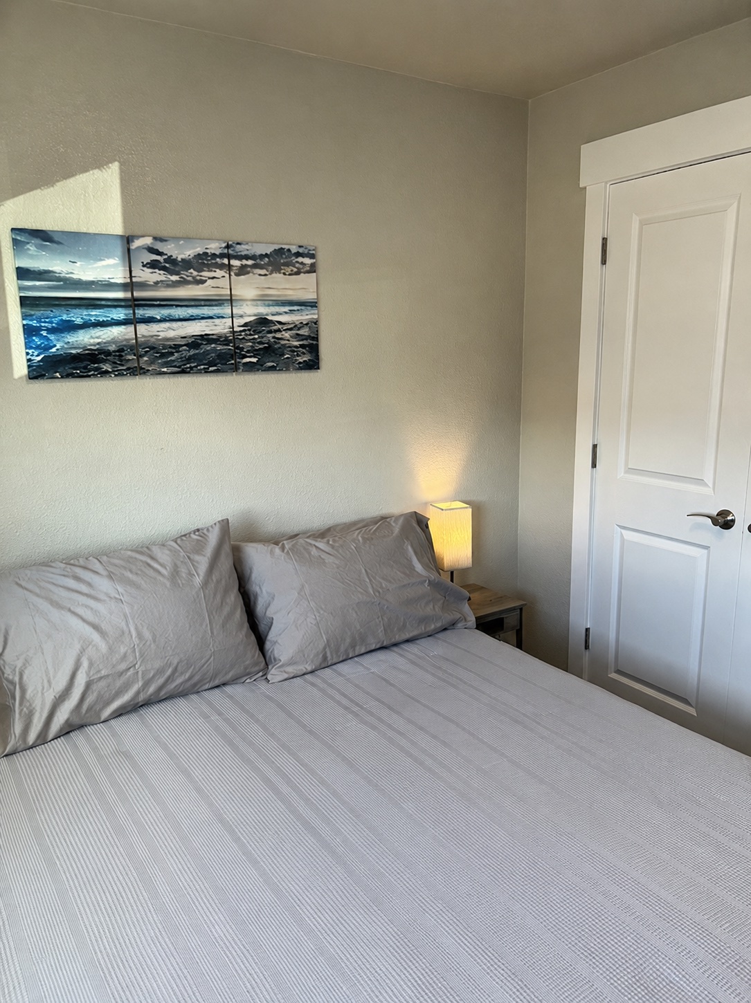 Bedroom with a queen bed, coastal wall art, and closet